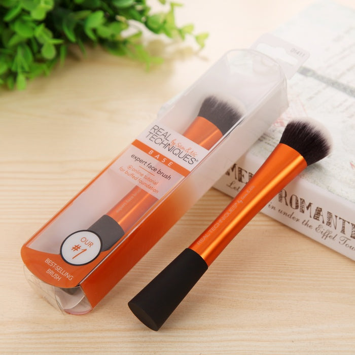 Real Techniques makeup brush with packaging on a wooden surface