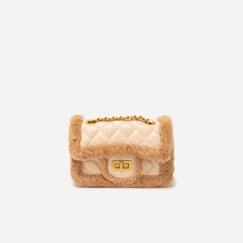 Small quilted handbag with fur trim on a white background