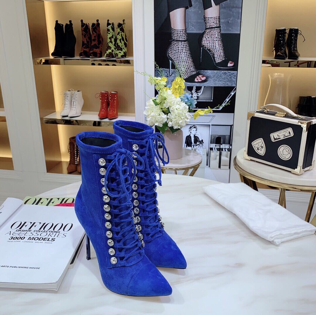 Blue suede high-heeled boots with decorative laces on a table with a magazine in a store setting.