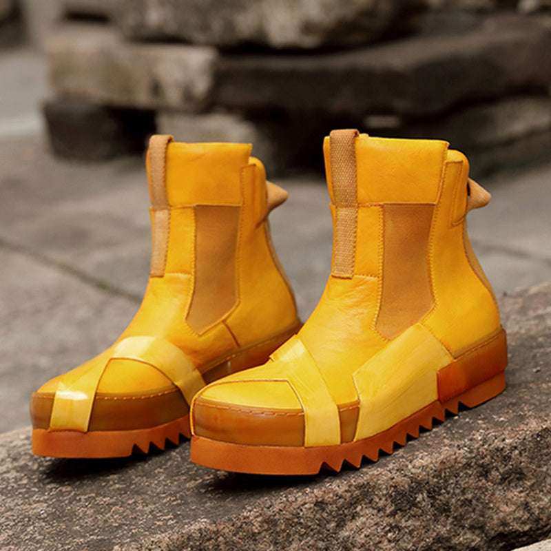 Pair of yellow rubber boots with brown soles on a stone surface.