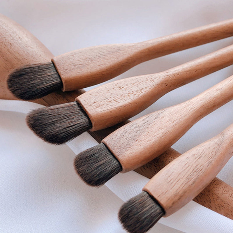 Set of makeup brushes with wooden handles and black bristles on a light background