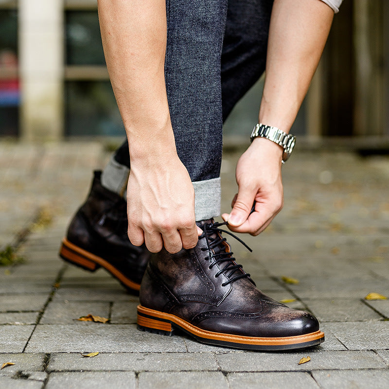 Person tying a brown leather shoe on a sidewalk