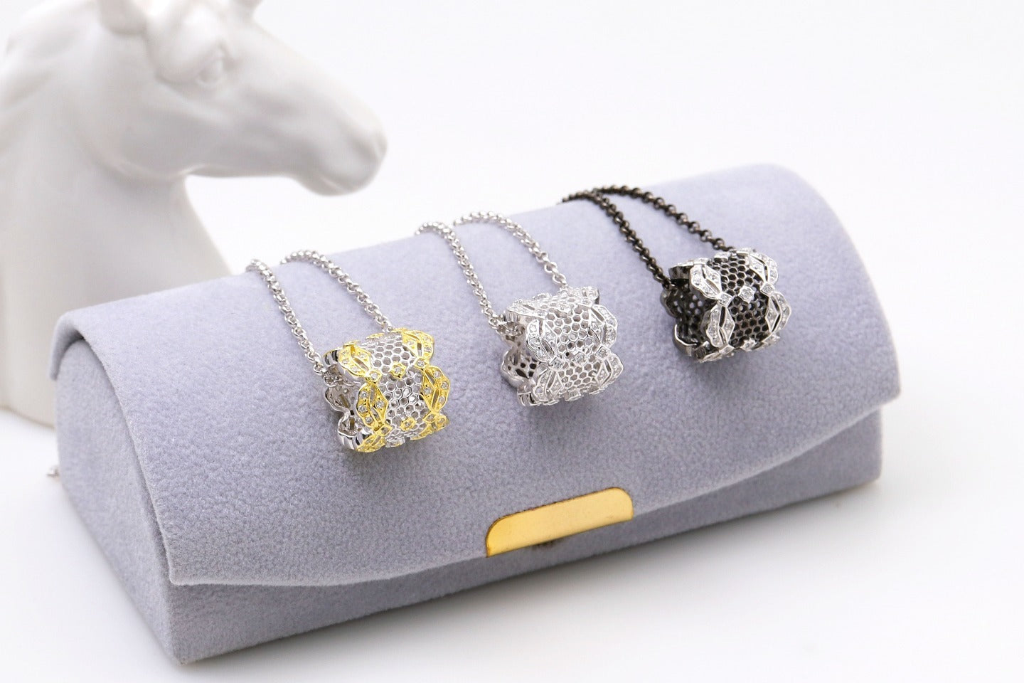 Three necklaces on a gray velvet display pillow with a white background