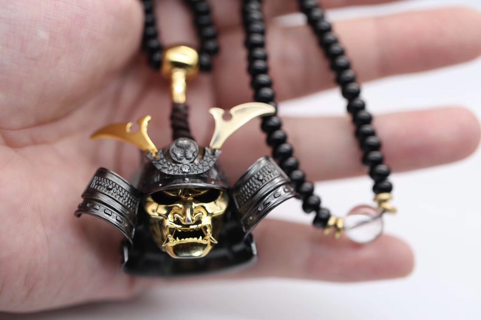 Gold and silver skull pendant with black beads on a hand
