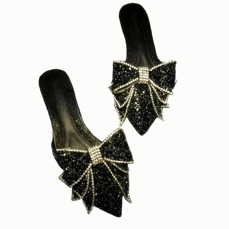 Black glittery shoes with bow designs on a white background