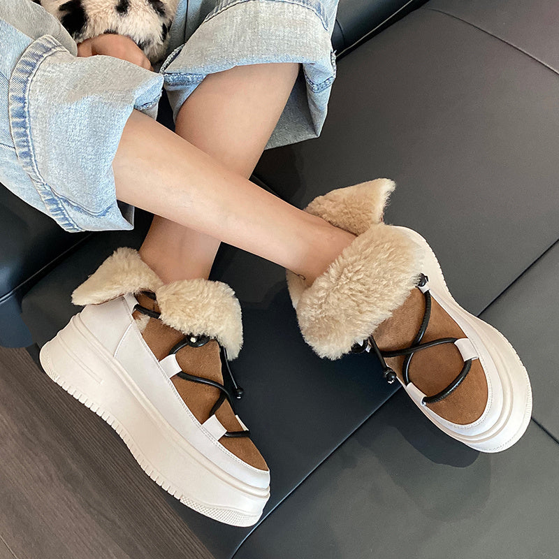 Person wearing brown and white platform shoes with fluffy accents on a dark surface.