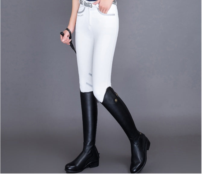 Person wearing white equestrian pants and black riding boots on a gray background