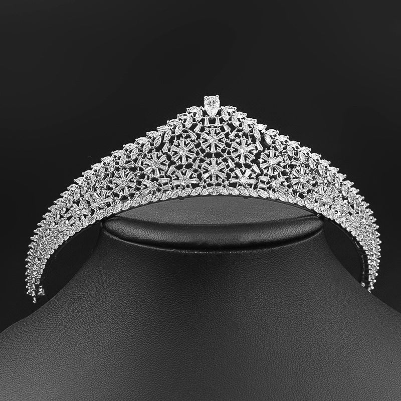 Silver tiara on a black stand against a black background