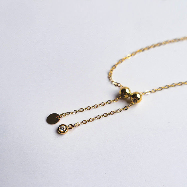 Gold necklace with three small pendants on a white background