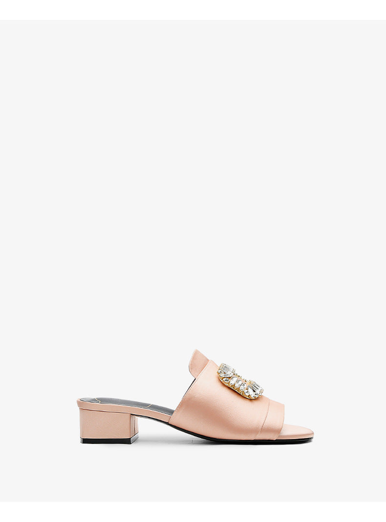 Pink sandal with a decorative buckle on a white background