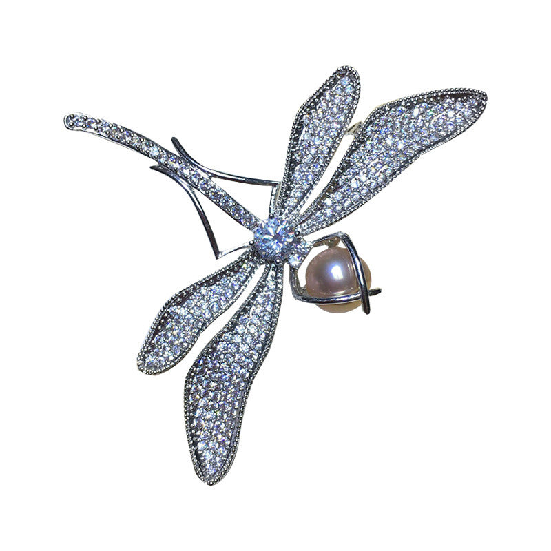Dragonfly-shaped jewelry piece with gemstones on a white background