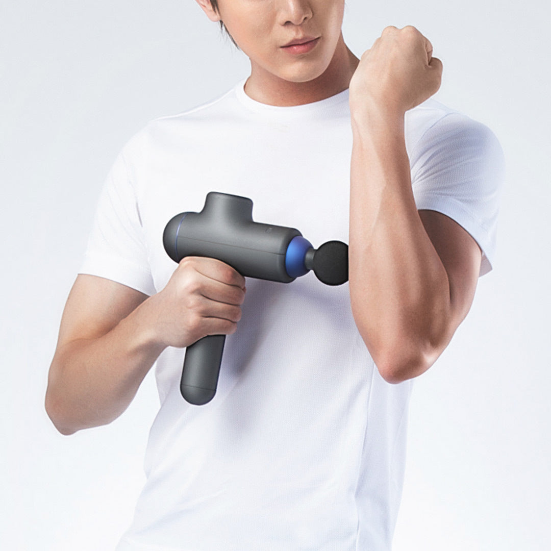 Person using a handheld massage gun on their arm against a white background