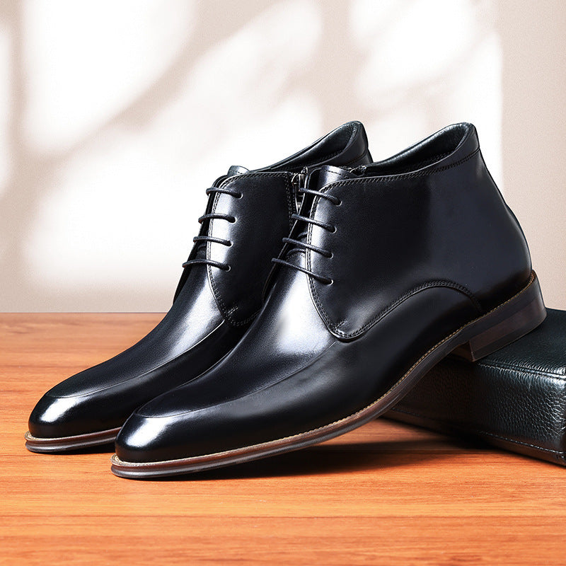Pair of black dress shoes on a wooden surface with a neutral background