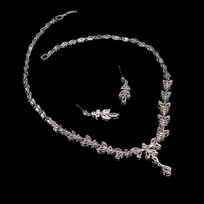 Silver jewelry set with necklace, bracelet, and earrings on a black background