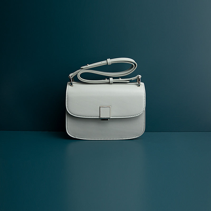 White handbag with a silver buckle on a dark blue background