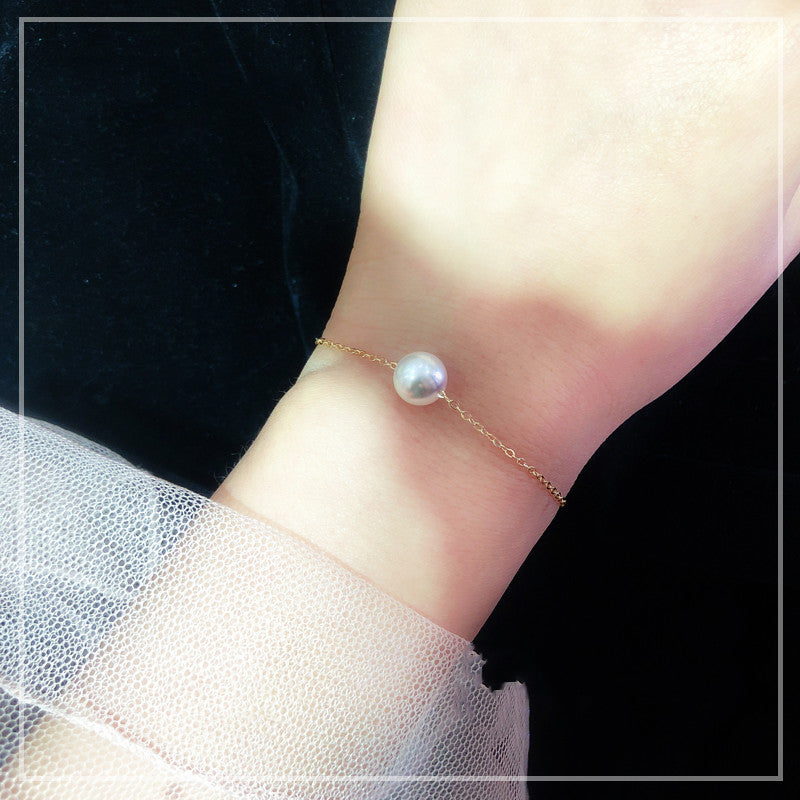 Pearl bracelet on a wrist with a black background