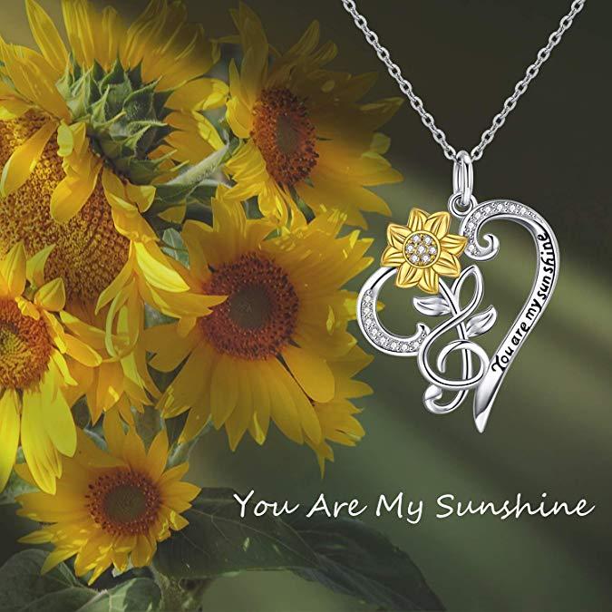 Silver necklace with heart and sunflower pendant among sunflowers with 'You Are My Sunshine' text.