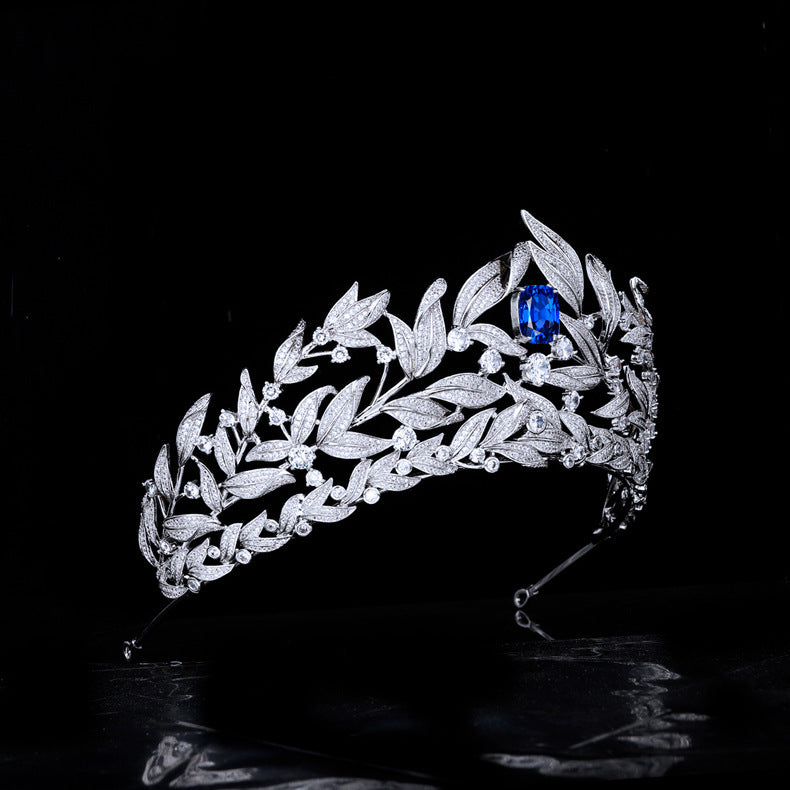 Silver tiara with a blue gemstone on a black background