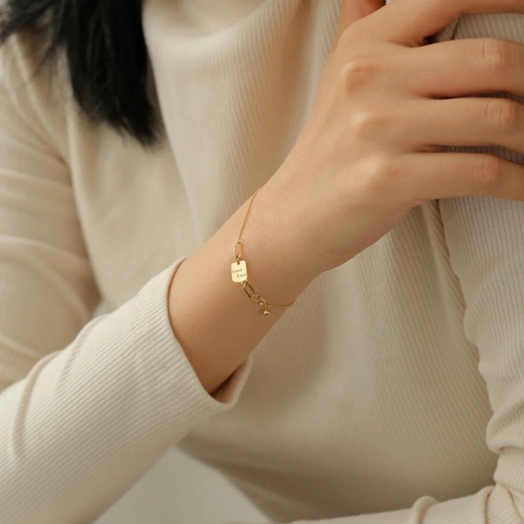 Gold bracelet on a person's wrist with a neutral background