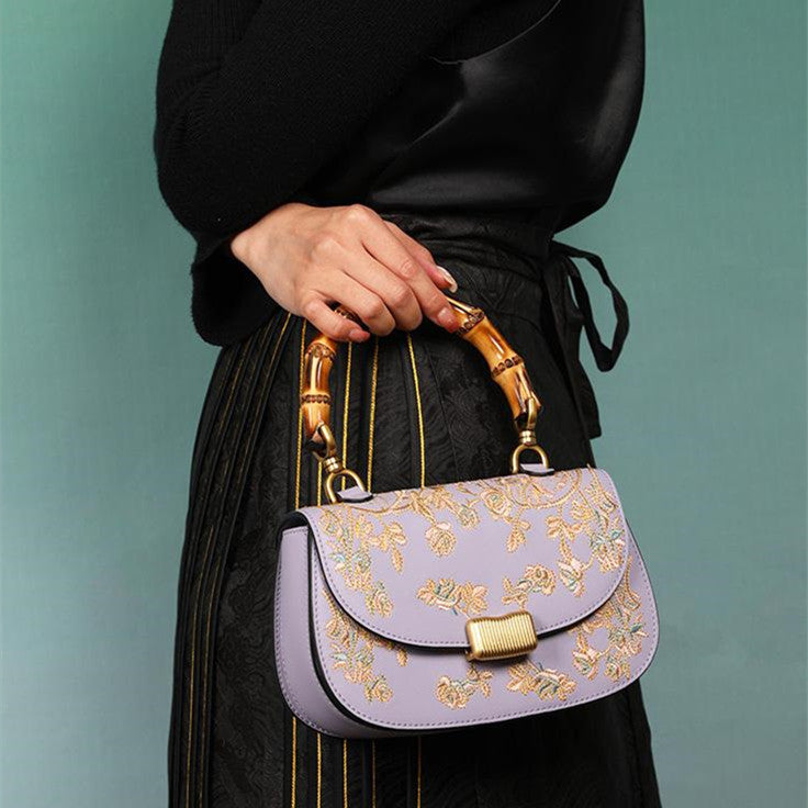 Person holding a purple handbag with gold accents against a teal background