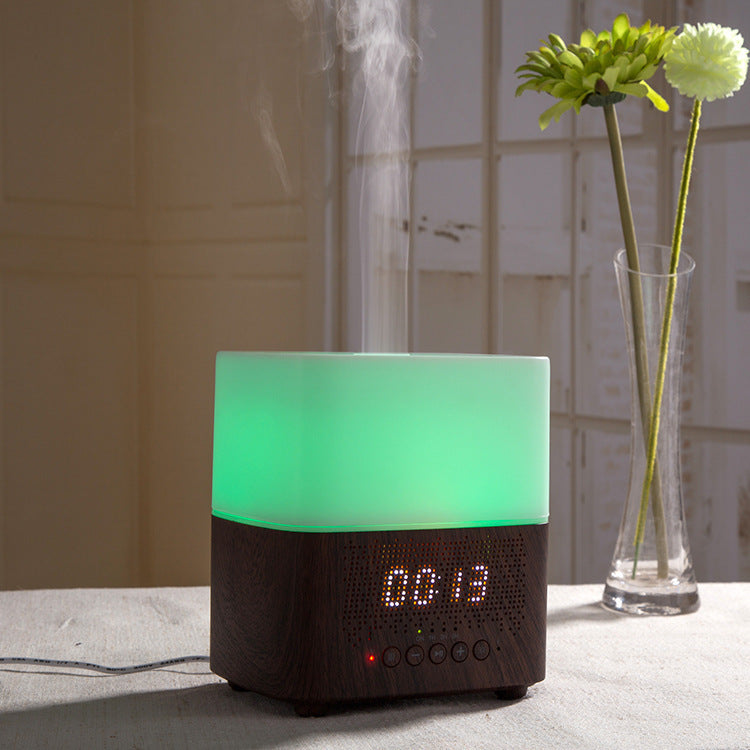 Humidifier with digital display on a surface, next to a vase with flowers.