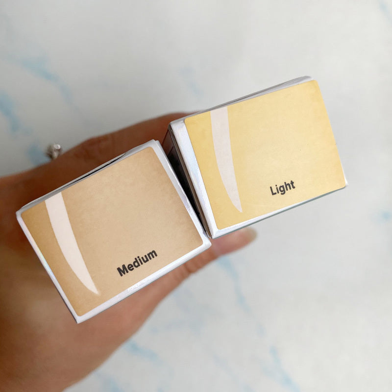 Two makeup sample boxes labeled 'Medium' and 'Light' held by a hand against a light background.