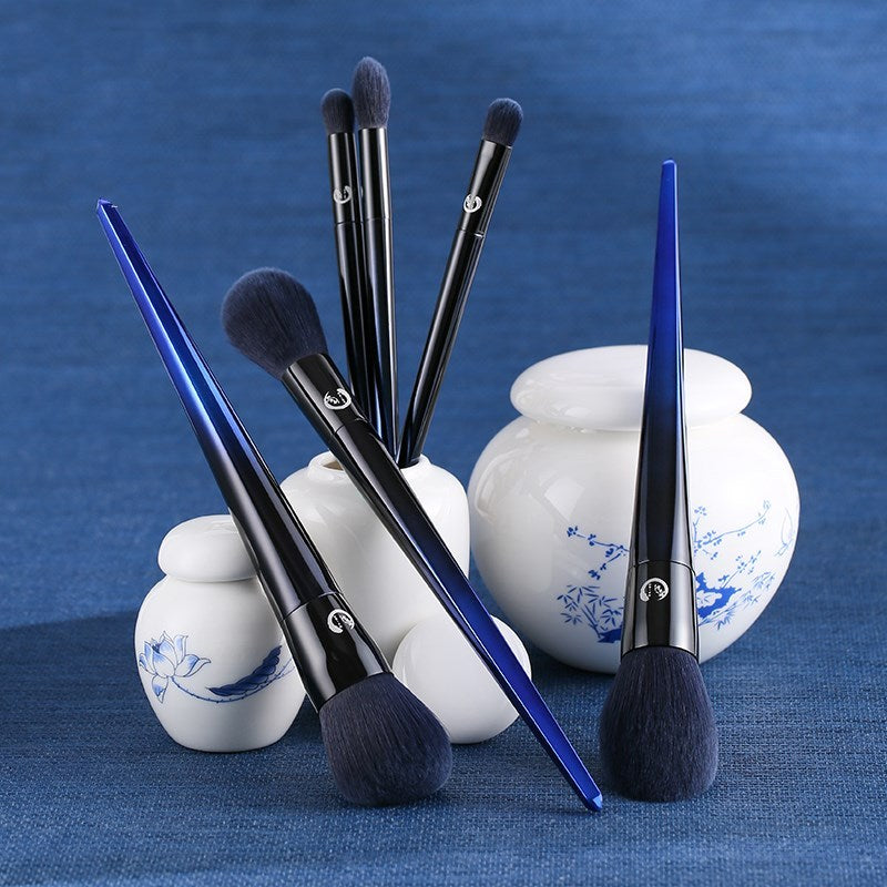 Set of makeup brushes with blue handles and black bristles on a blue background