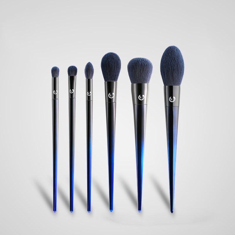 Set of makeup brushes with blue and black handles on a light gray background