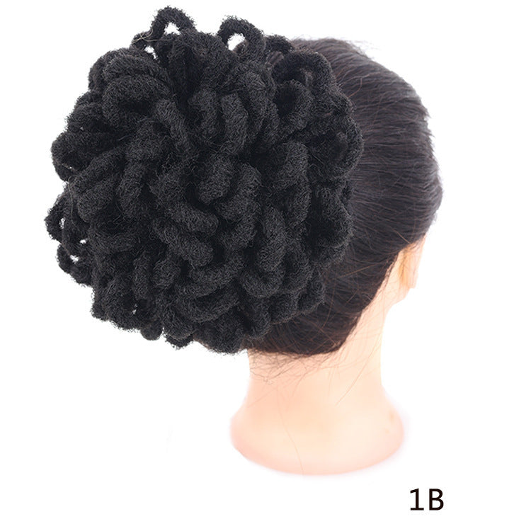 Black hair bun extension on a mannequin head with a white background