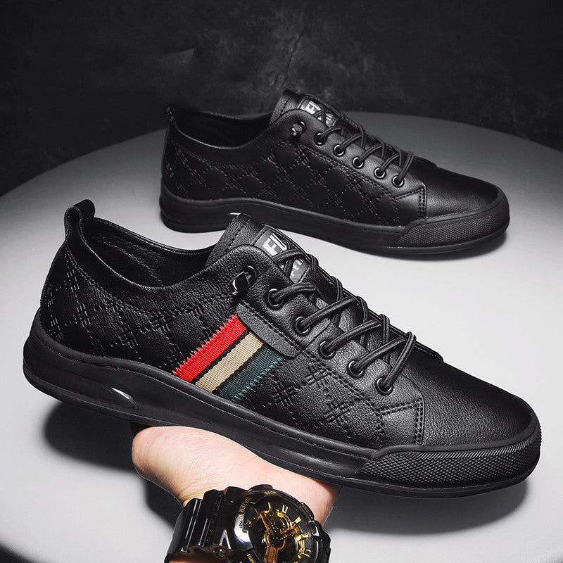 Black sneakers with a red and beige stripe held by a hand on a dark background