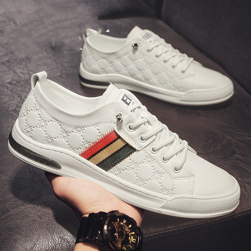 White sneakers with a patterned sole held by a hand on a dark surface