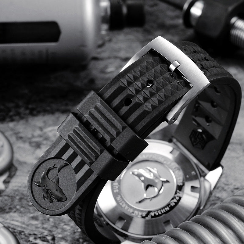 Close-up of a watch with a detailed black strap on a textured surface
