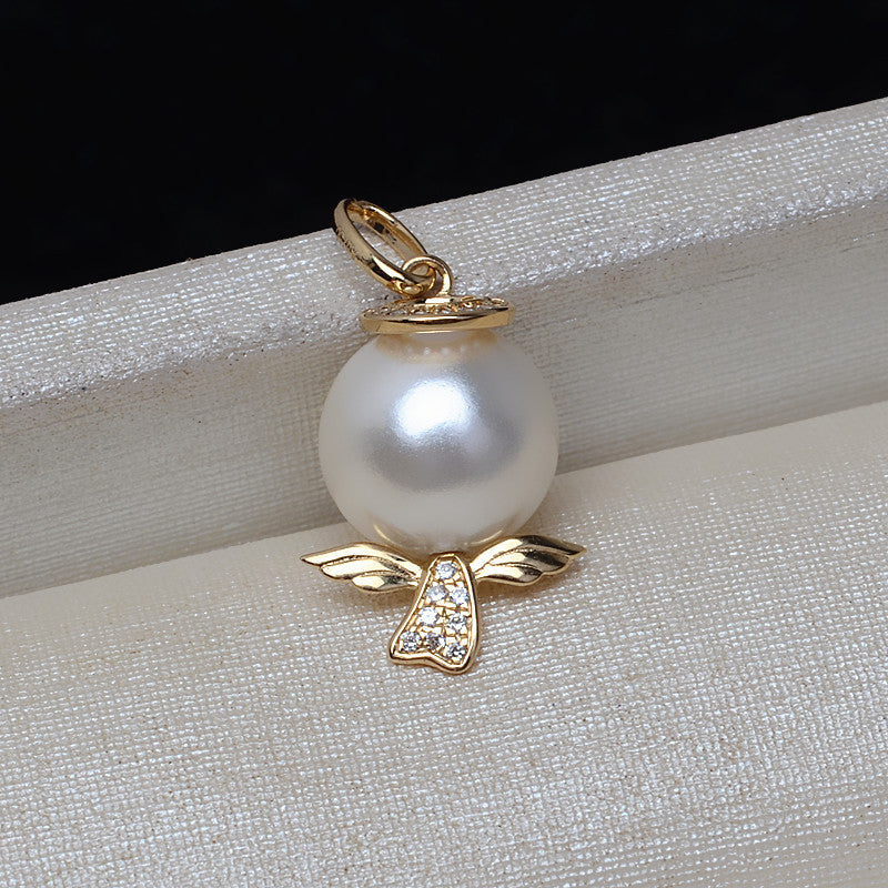Pearl pendant with gold wings on a textured surface