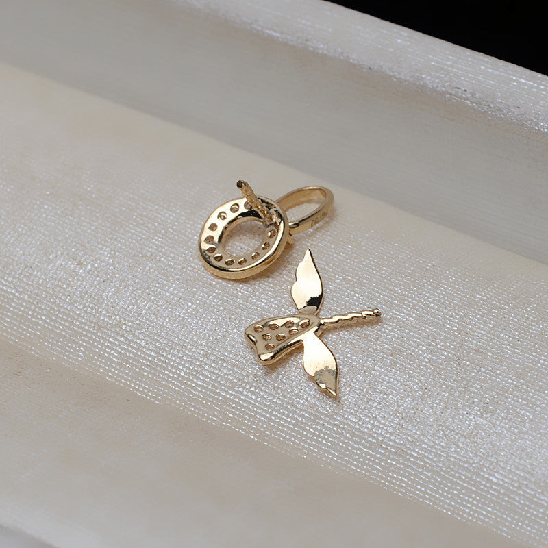 Gold butterfly pendant and ring on a white fabric background