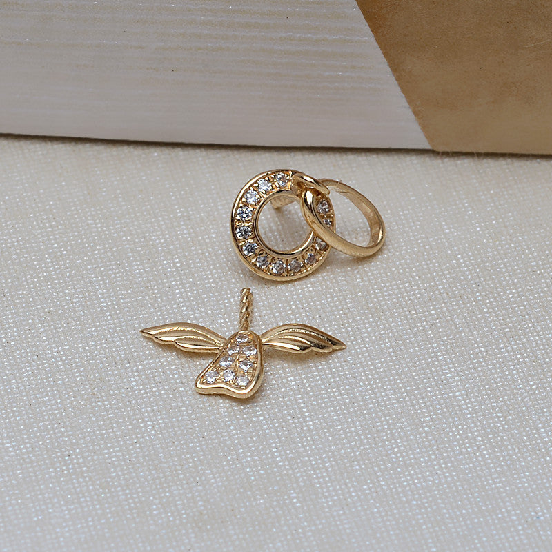 Gold earrings with heart and leaf design on a textured surface