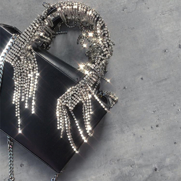 Black handbag with silver beaded chain on a gray surface