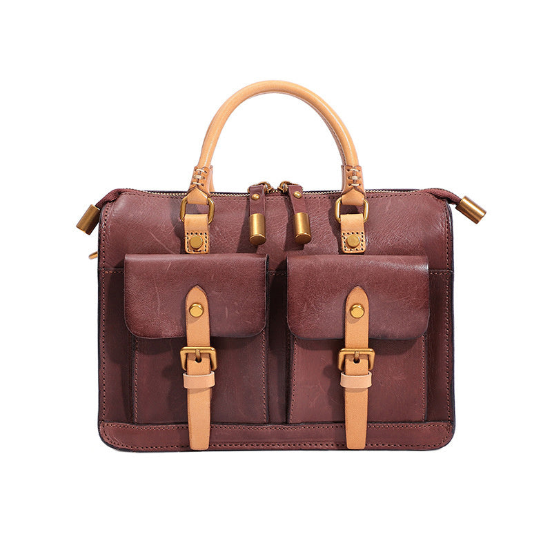 Brown leather satchel with tan straps and handles on a white background