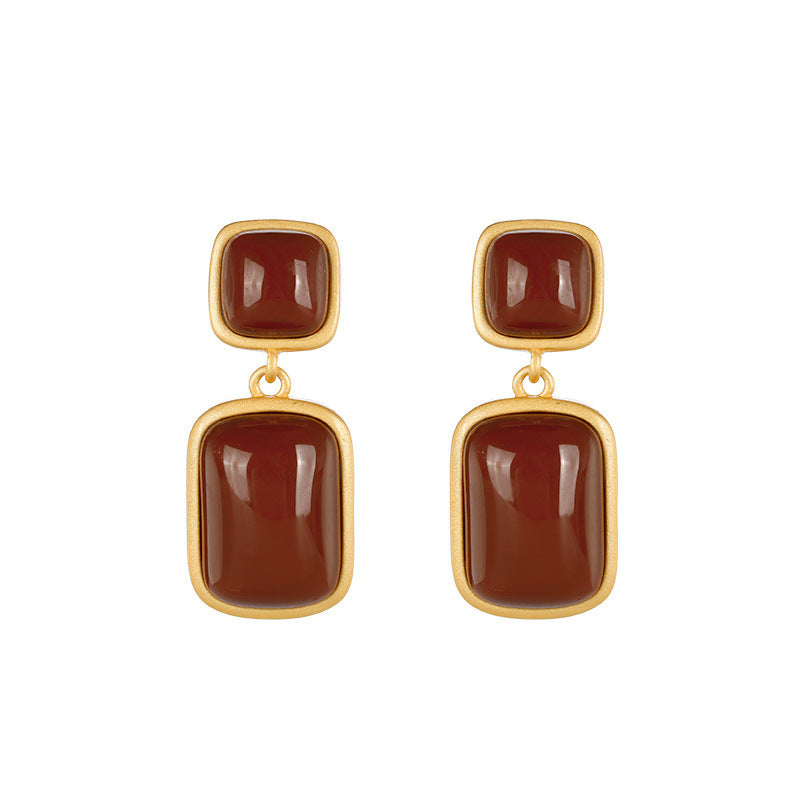 Gold earrings with brown square stones on a white background