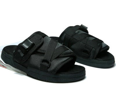Black sandals with strap details on a white background