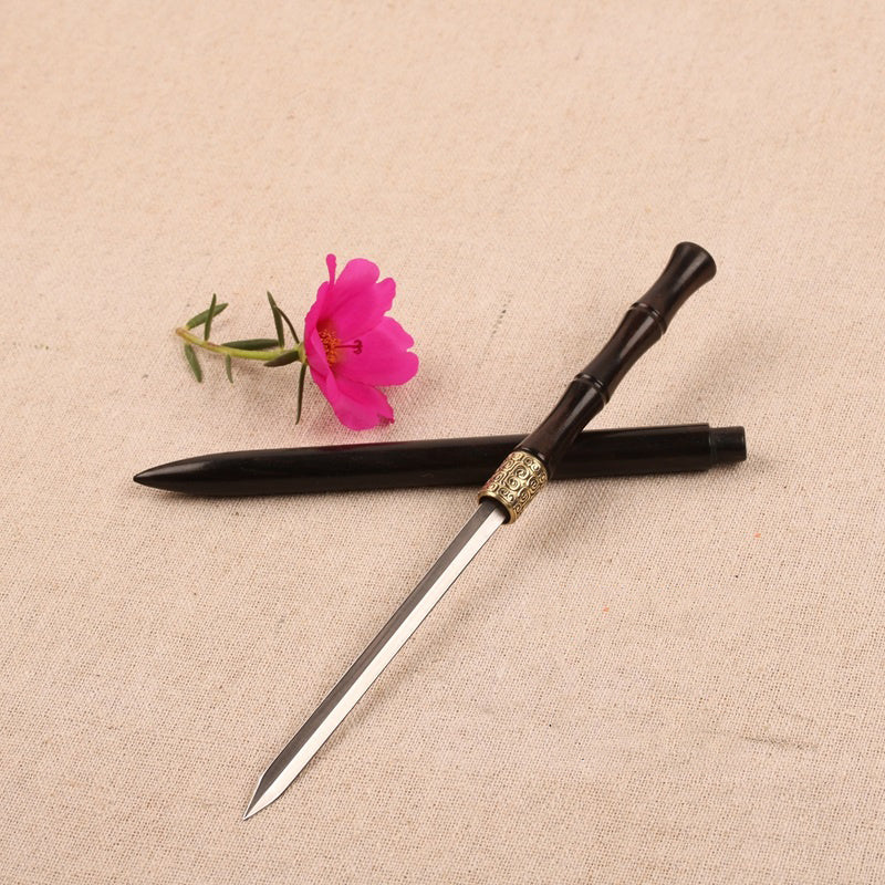 Traditional Chinese sword with black handle and gold accent on a beige fabric background with a pink flower.
