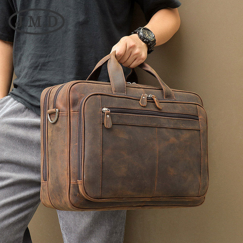 Person holding a brown leather briefcase against a plain background