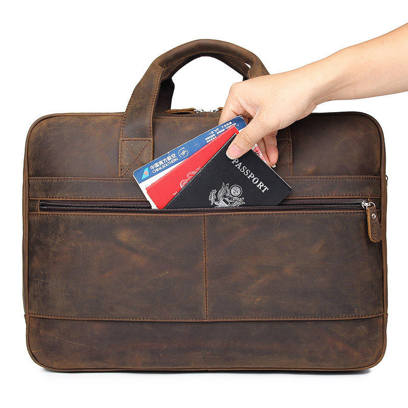 Brown leather briefcase with a hand placing a passport and cards inside on a white background