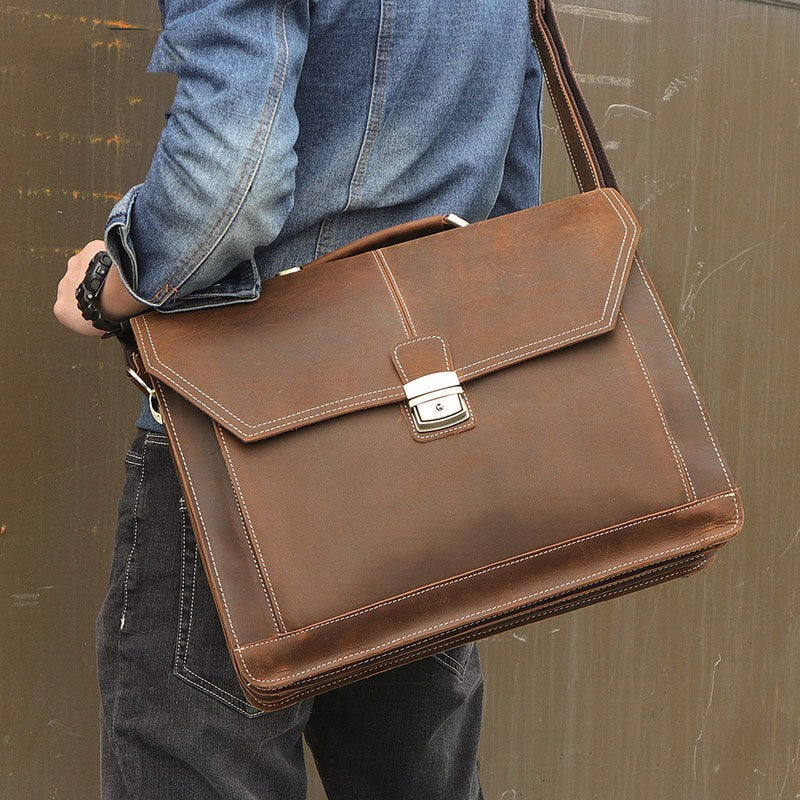 Person holding a brown leather briefcase against a plain background