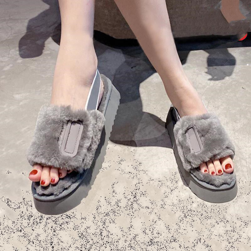 Gray fuzzy slippers worn by a person on a concrete surface