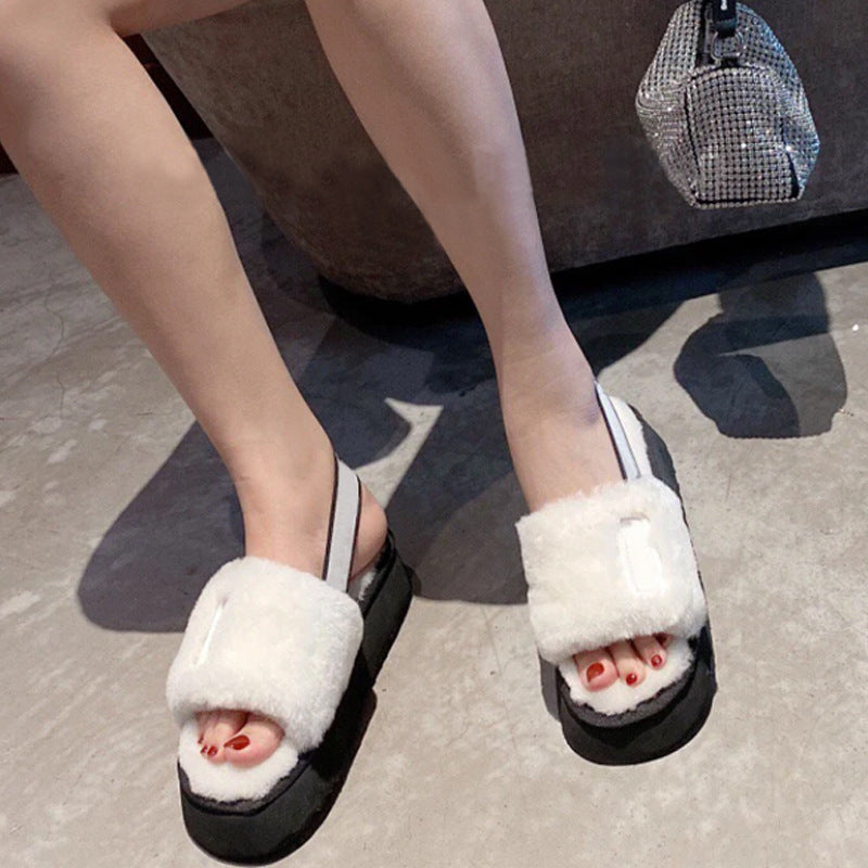 Person wearing black sandals with white fuzzy tops on a gray floor.
