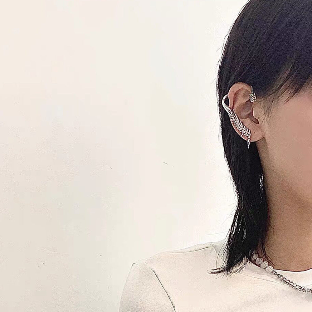 Person wearing a silver ear cuff with a white background
