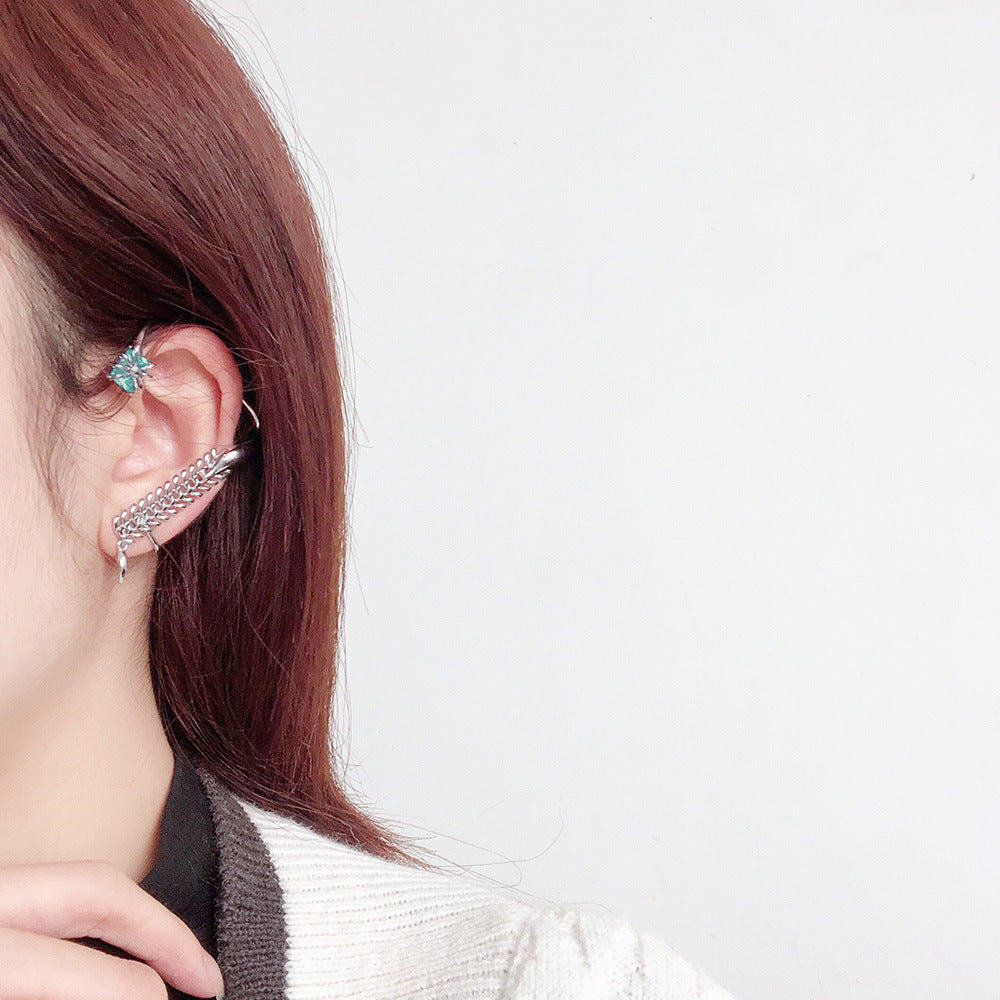 Close-up of an ear with a decorative earring on a plain background