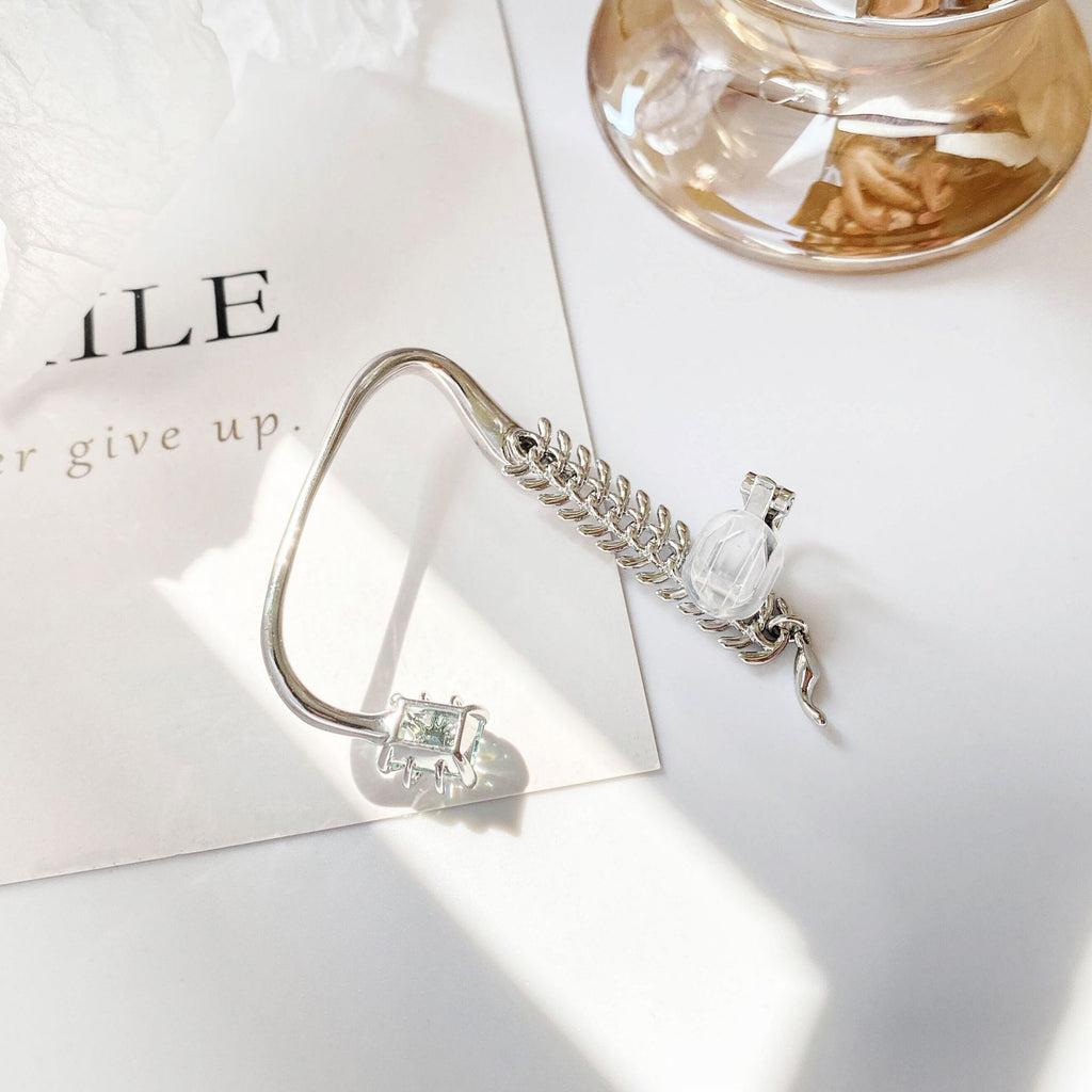 Silver bracelet with a clear gemstone on a white surface