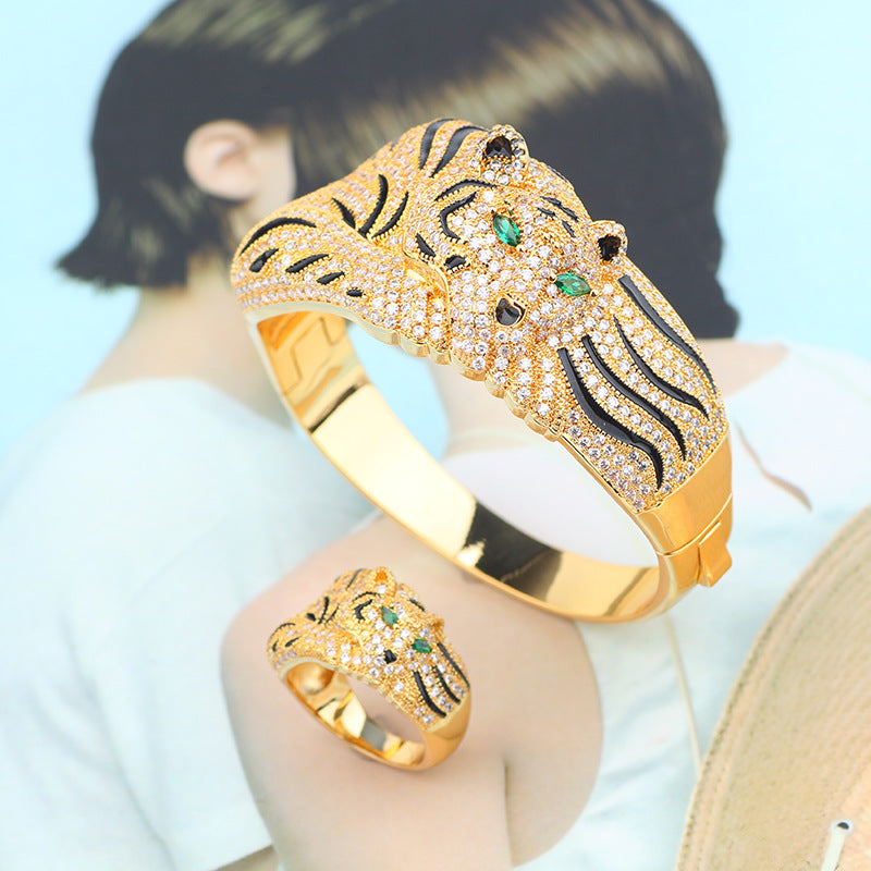 Gold bracelet and ring set with tiger design on a light blue background