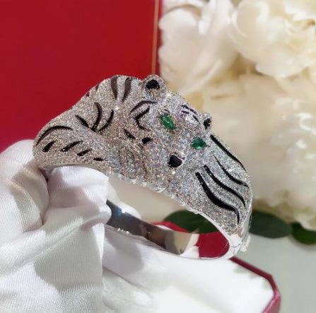 Silver tiger-shaped ring with gemstones on a white stand against a red background